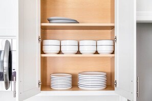 A kitchen cabinet with multiple shelves, each holding bowls and plates.