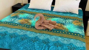 A bed with a blue patterned bedspread, two white pillows, and a brown towel. - Les 3 E (Englebelmer)