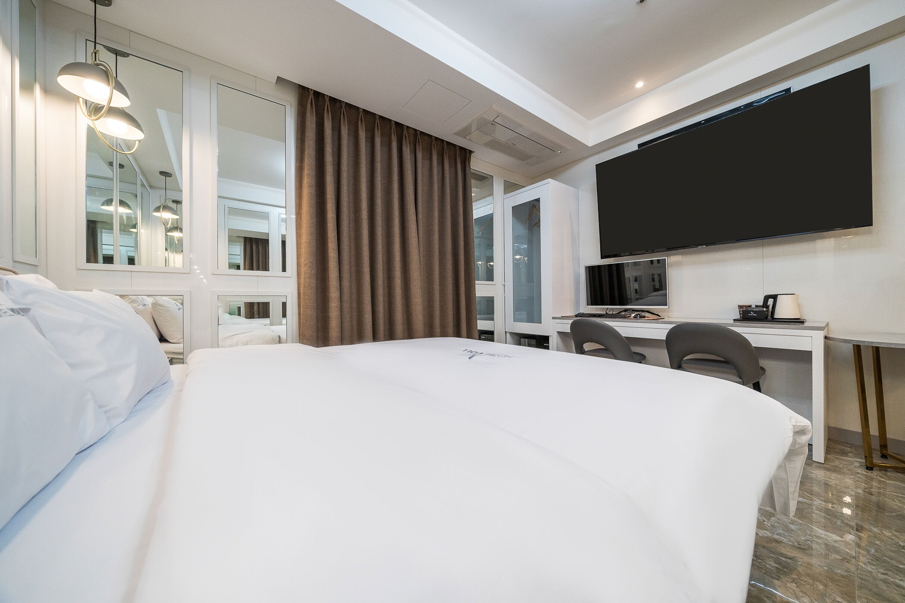 Ein Hotelzimmer mit einem großen Bett, einem Schreibtisch mit Computer und einem Flachbildfernseher.