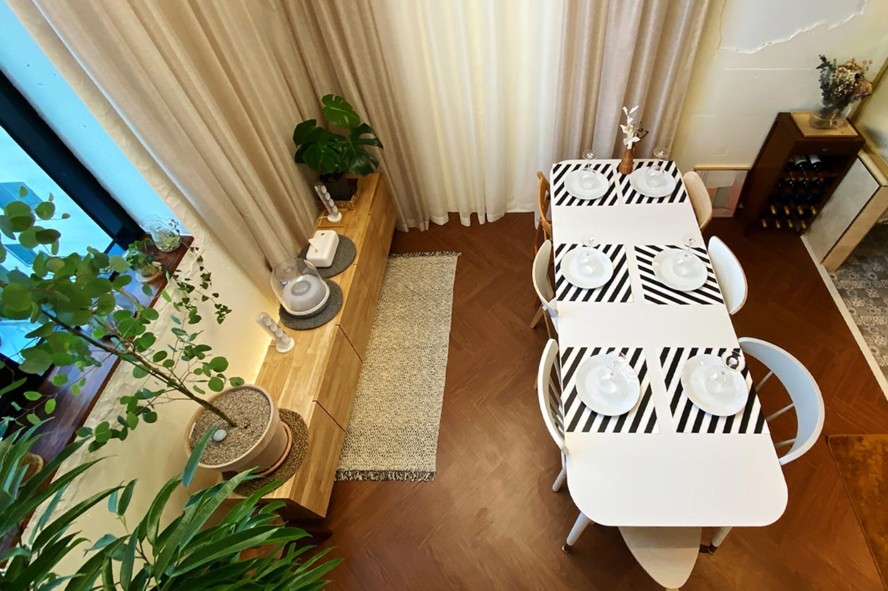A dining area with a table set for four, a potted plant, and a wine rack.