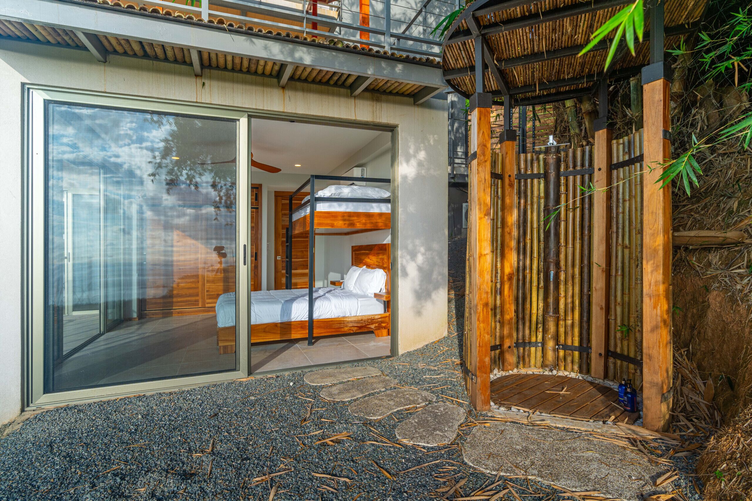 Une chambre moderne avec une porte en verre donnant sur un balcon, un lit en bois et une entrée en bambou.