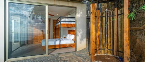 Une chambre moderne avec une porte en verre donnant sur un balcon, un lit en bois et une entrée en bambou.