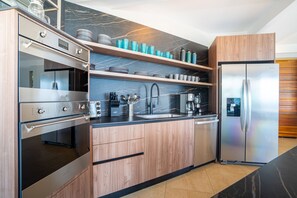 A modern kitchen with stainless steel appliances, wooden cabinetry, and marble backsplash. - Villa Vista del Mar by Pura Villas (Dominical)