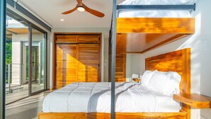Un dormitorio moderno con cabecera de cama de madera, ventilador de techo y vistas al exterior.