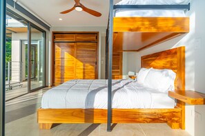 A modern bedroom with a wooden bed frame, a ceiling fan, and a view of the outdoors.