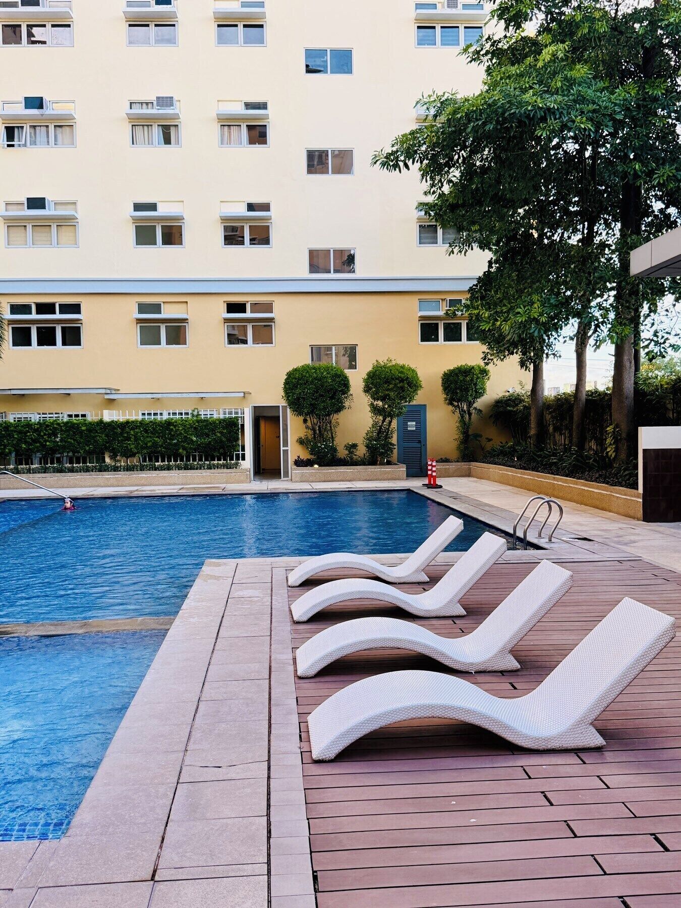 A swimming pool with lounge chairs and a building in the background.