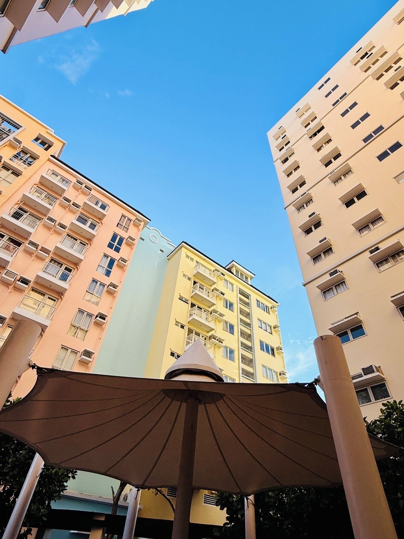 A multi-story residential building with balconies and a clear blue sky.