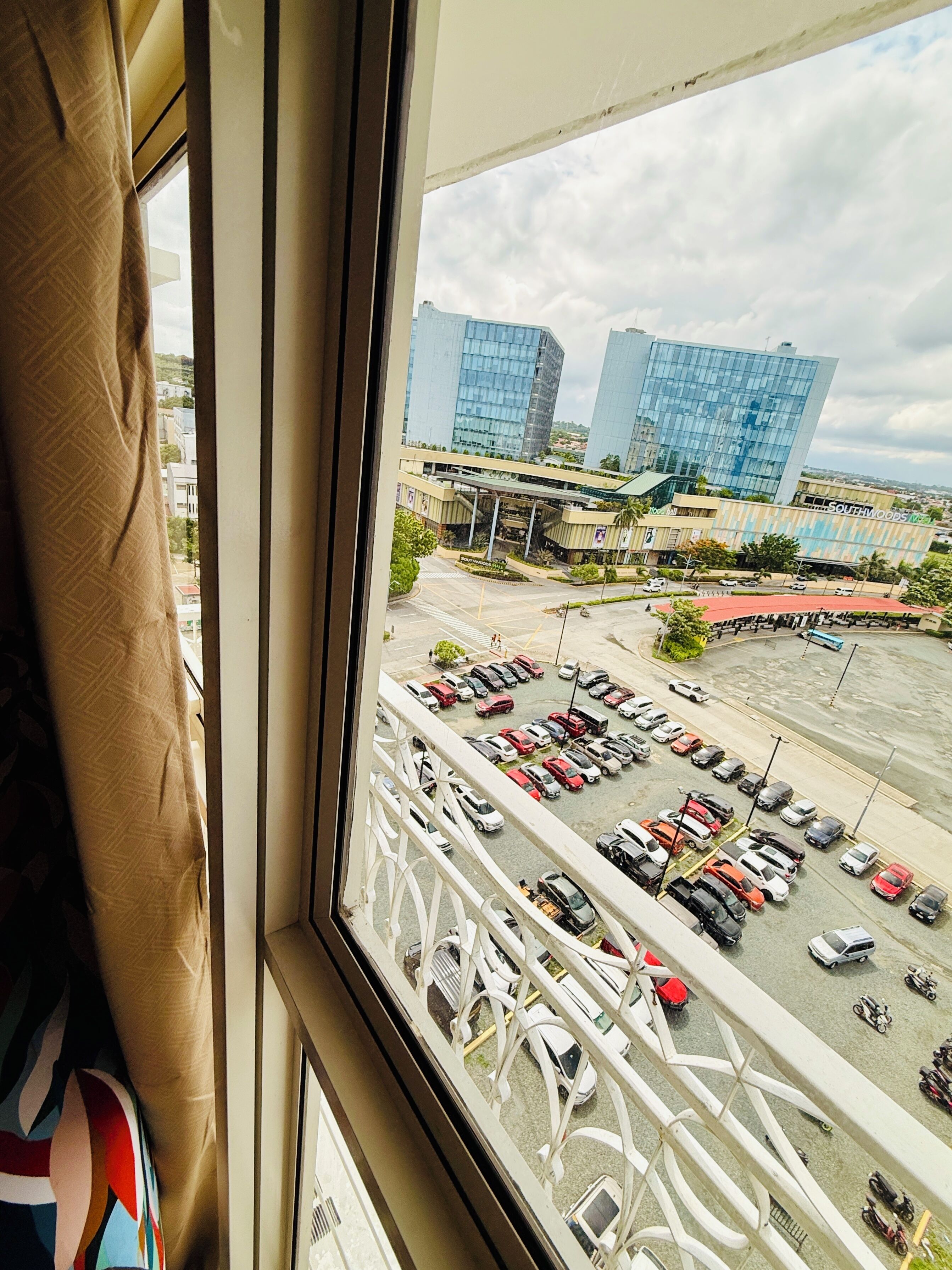 A view from a window overlooking a parking lot and a building with a modern design.