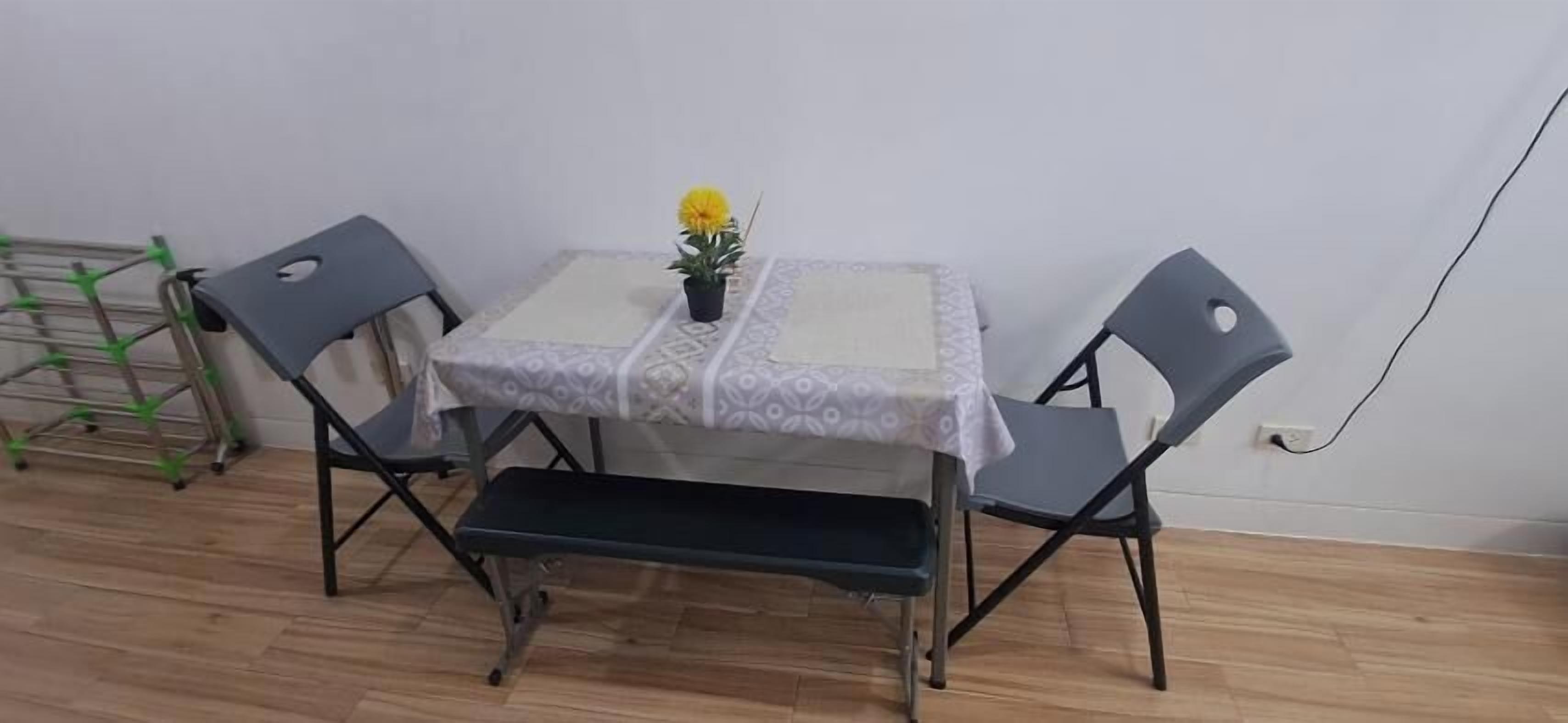 A small dining area with a table and two chairs, a bench, and a potted plant.