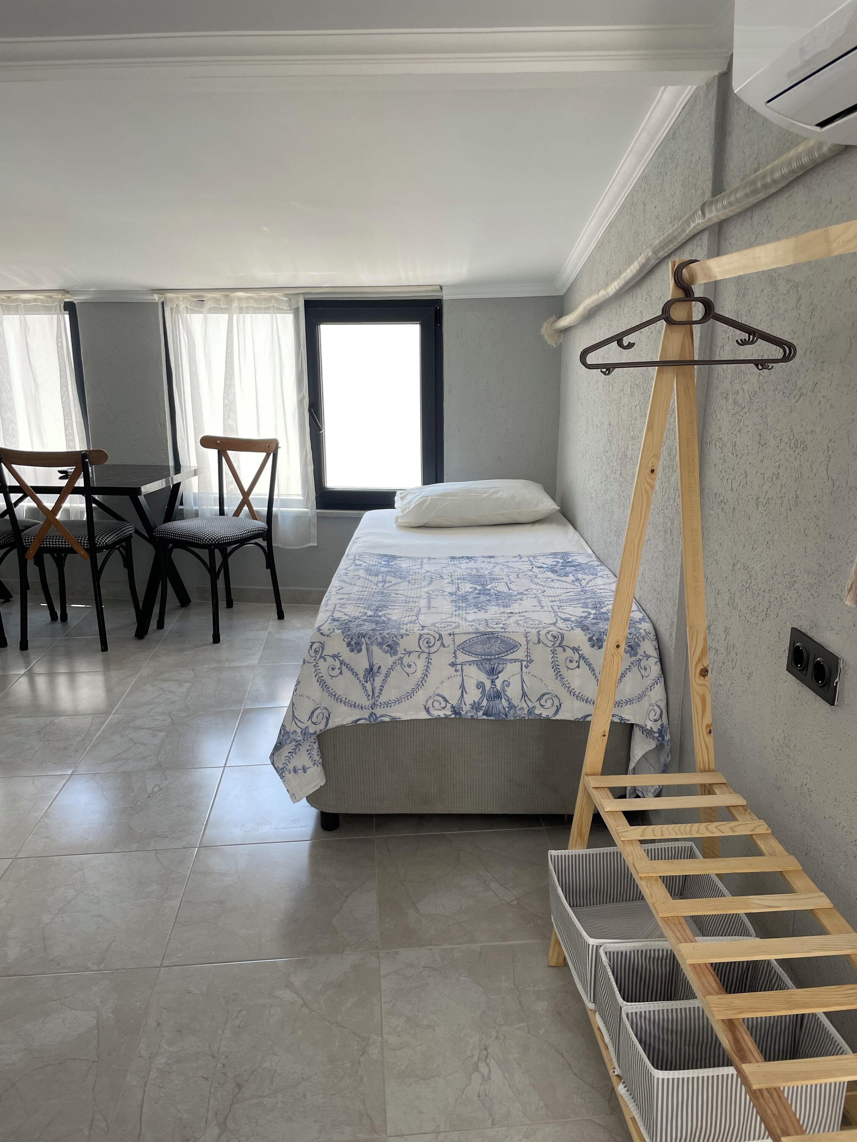 Ein Schlafzimmer mit einem Bett, einem Schreibtisch, zwei Stühlen, einem Fenster und einer Holzleiter.