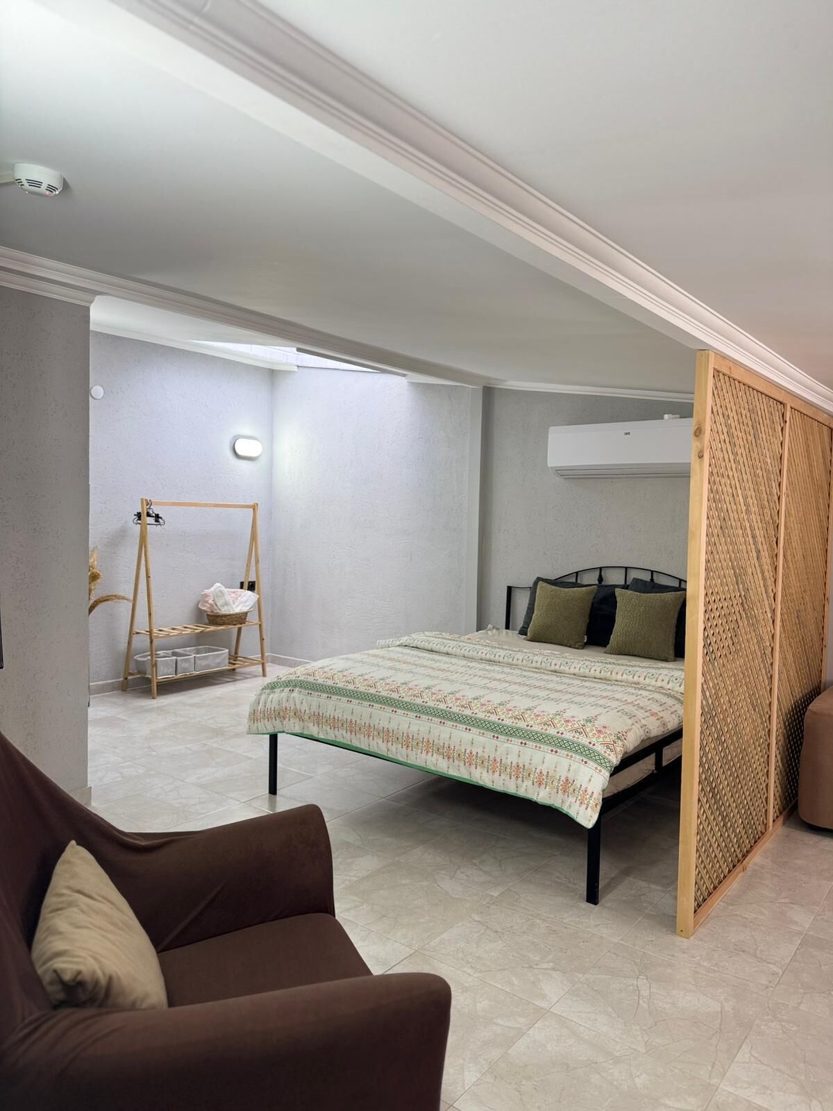 Ein Schlafzimmer mit einem Bett, einem Holzschrank, einer Couch und einem kleinen Tisch mit einem Korb.
