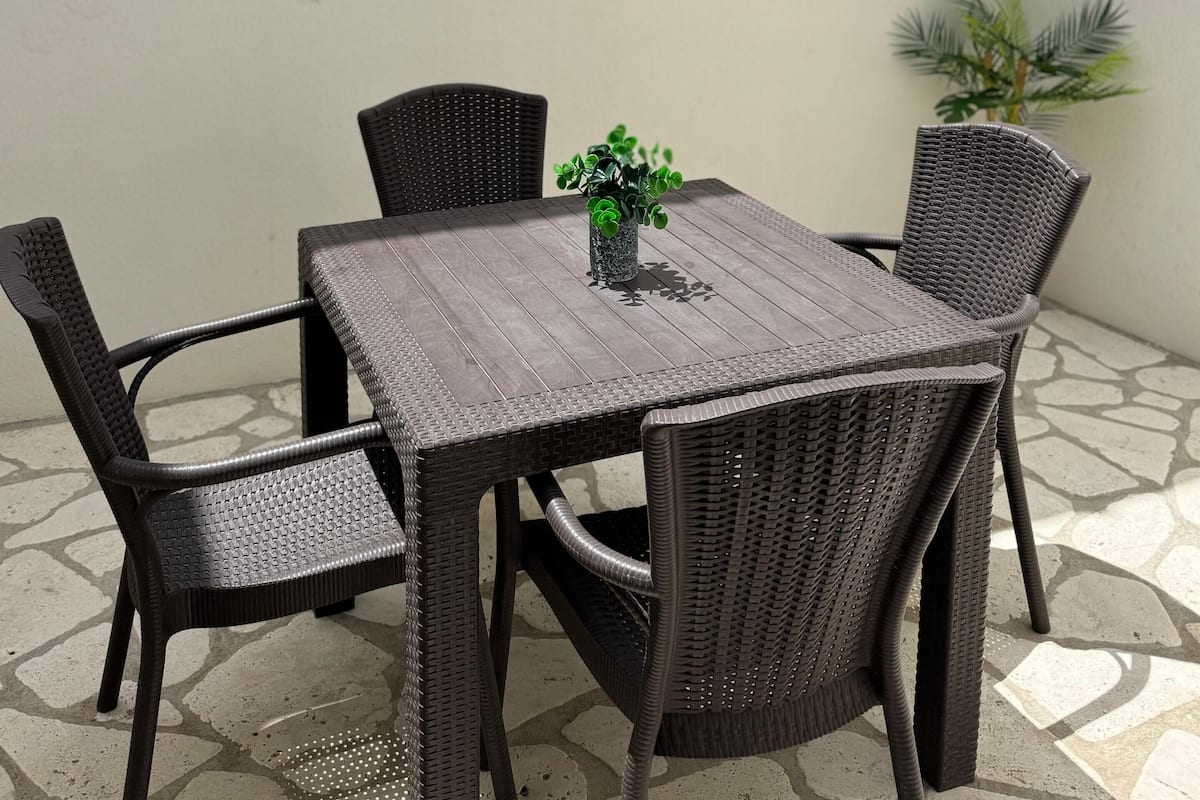 Uma sala de jantar com uma mesa quadrada e seis cadeiras de vime. Pratos decorativos adornam a parede atrás da mesa.