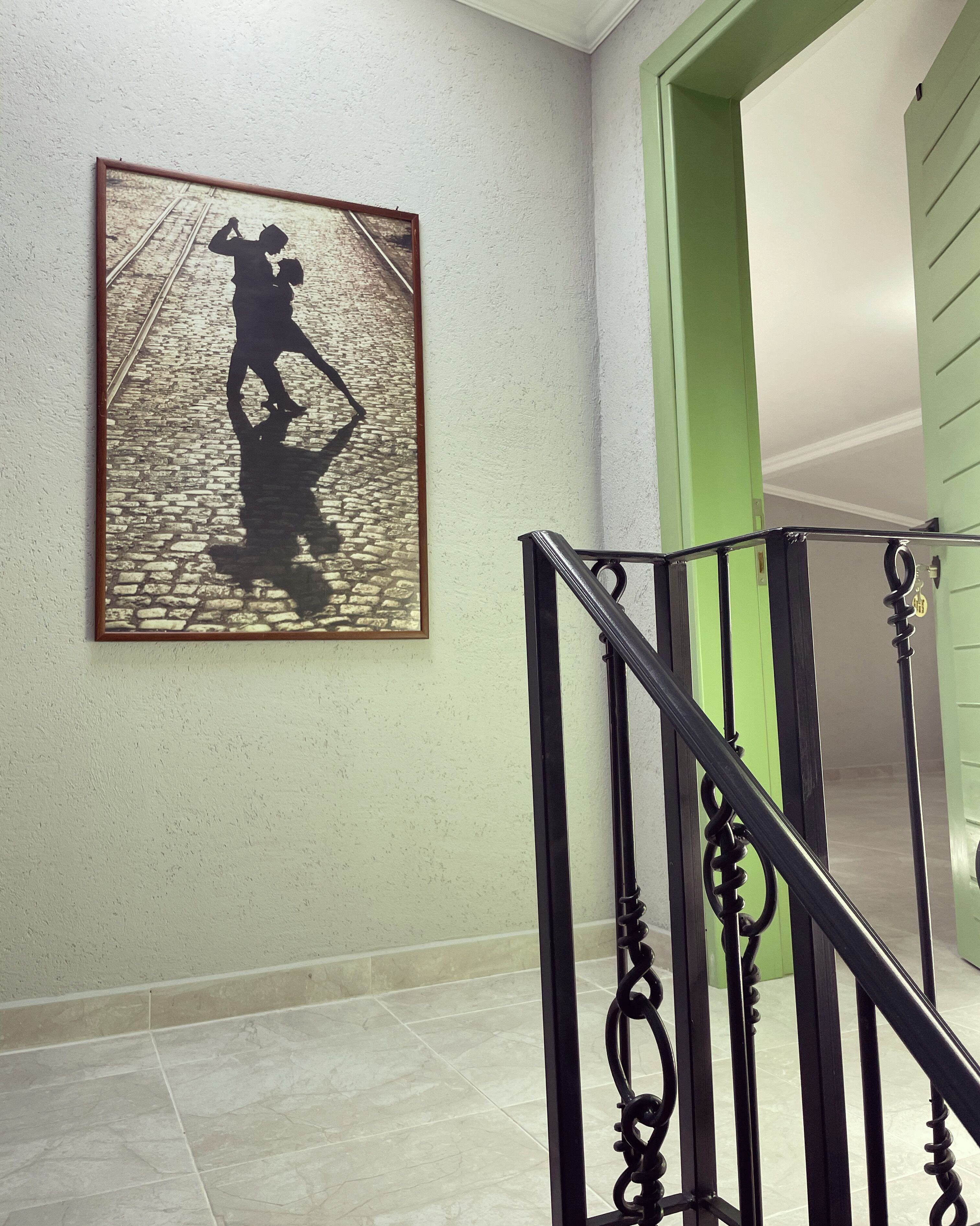 A staircase with a black handrail and a framed picture of a person on a cobblestone street.