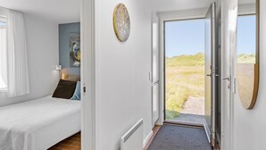 Een slaapkamer met een bed, nachtkastje, lamp en een schilderij aan de muur.