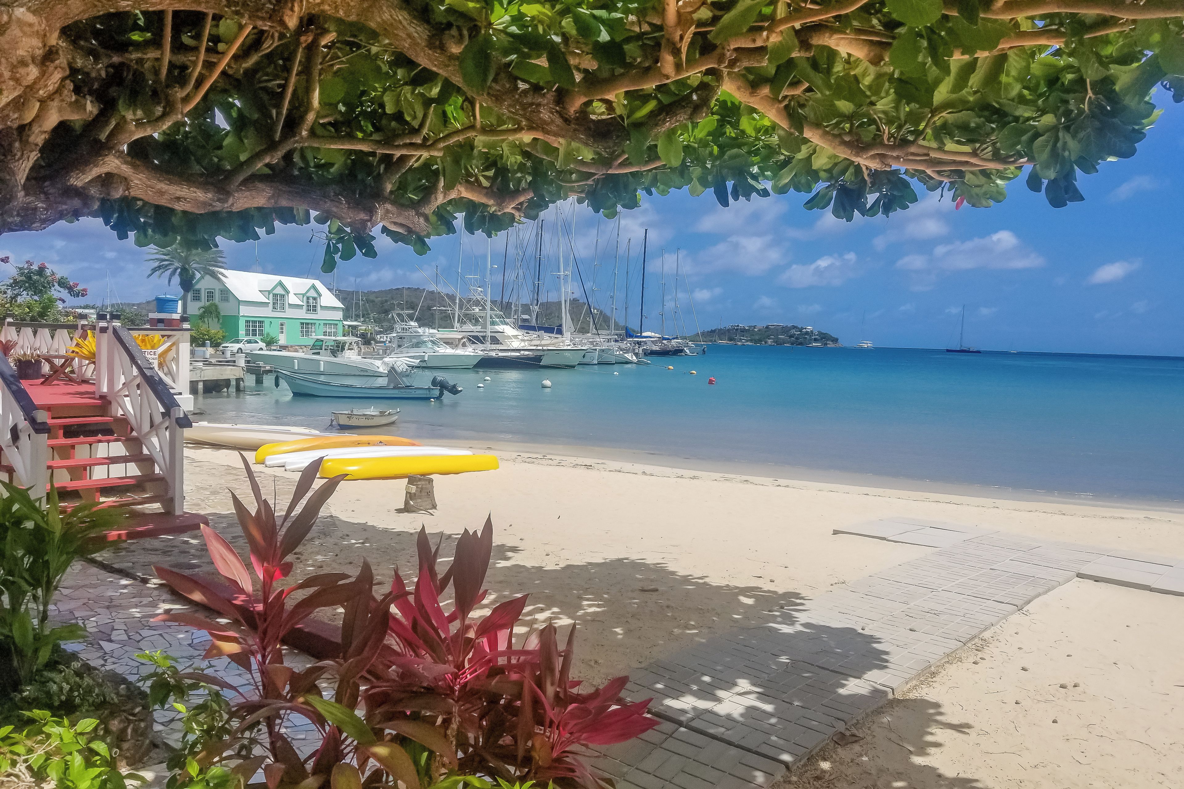Ein Strand mit Booten, einem Gebäude und einem Holzsteg.