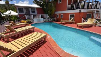 A swimming pool with wooden loungers and a red deck.