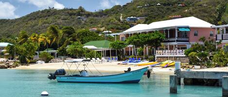 A coastal hotel with a beach, lounge chairs, and a boat docked in the water.