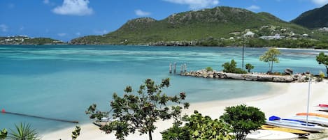 Une plage à l’eau turquoise et limpide, un rivage sablonneux et quelques bateaux.