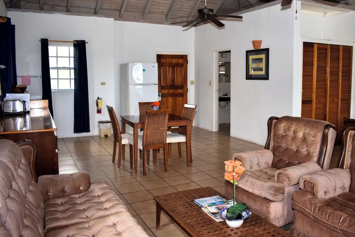 Una sala de estar con comedor, un ventilador de techo y un refrigerador.