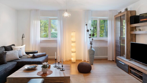 Ein modernes Wohnzimmer mit einer Couch, einem Couchtisch, einem Fernseher und einer großen Vase.