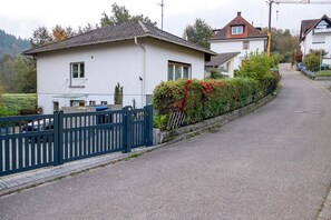 Eine Wohnstraße mit Häusern, einem blauen Zaun und blauem Himmel.