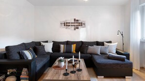 Ein modernes Wohnzimmer mit einem Ecksofa, einem Couchtisch und einem an der Wand befestigten Kunstwerk.