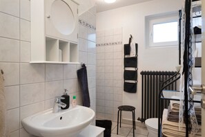 Ein Badezimmer mit Waschbecken, Toilette, Handtuchhalter und Heizkörper.