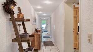 Ein Flur mit Holzregal, einer Wanddekoration und einer Tür zu einem Zimmer.