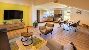 Un espacio de estar moderno con una televisión de pantalla plana, una zona de comedor y una cocina.