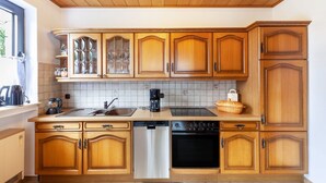 A kitchen with wooden cabinets, a dishwasher, an oven, and a coffee maker. - Rosi's Apartment with Mountain View, Shared Terrace and Wi-Fi (Daun)