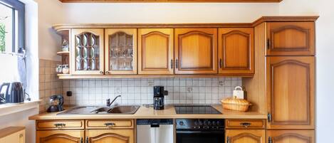 Een keuken met houten kastjes, een vaatwasser, een oven en een koffiezetapparaat.