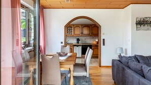 A modern kitchen with wooden cabinets, a dining table with chairs, and a sofa in a living area. - Rosi's Apartment with Mountain View, Shared Terrace and Wi-Fi (Daun)