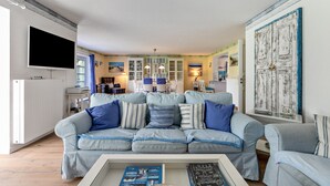 Un salon avec un canapé bleu clair, un téléviseur à écran plat et une table basse sur laquelle sont posés des magazines.