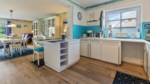 Une cuisine avec des meubles blancs, un îlot central et une fenêtre donnant sur un beau paysage.