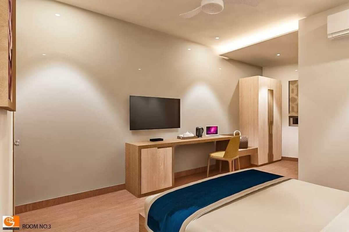 Una camera d'albergo moderna con un letto, una scrivania con una sedia, una TV e un armadio.