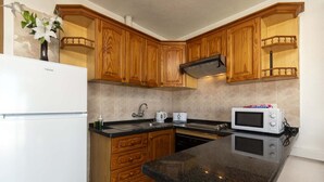 A kitchen with wooden cabinets, a white refrigerator, a microwave, and a sink. - Las Floritas 4 (Playa de Las Americas)