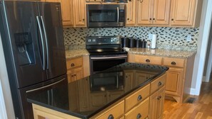 A kitchen with wooden cabinets, a black refrigerator, a microwave, and a stove.