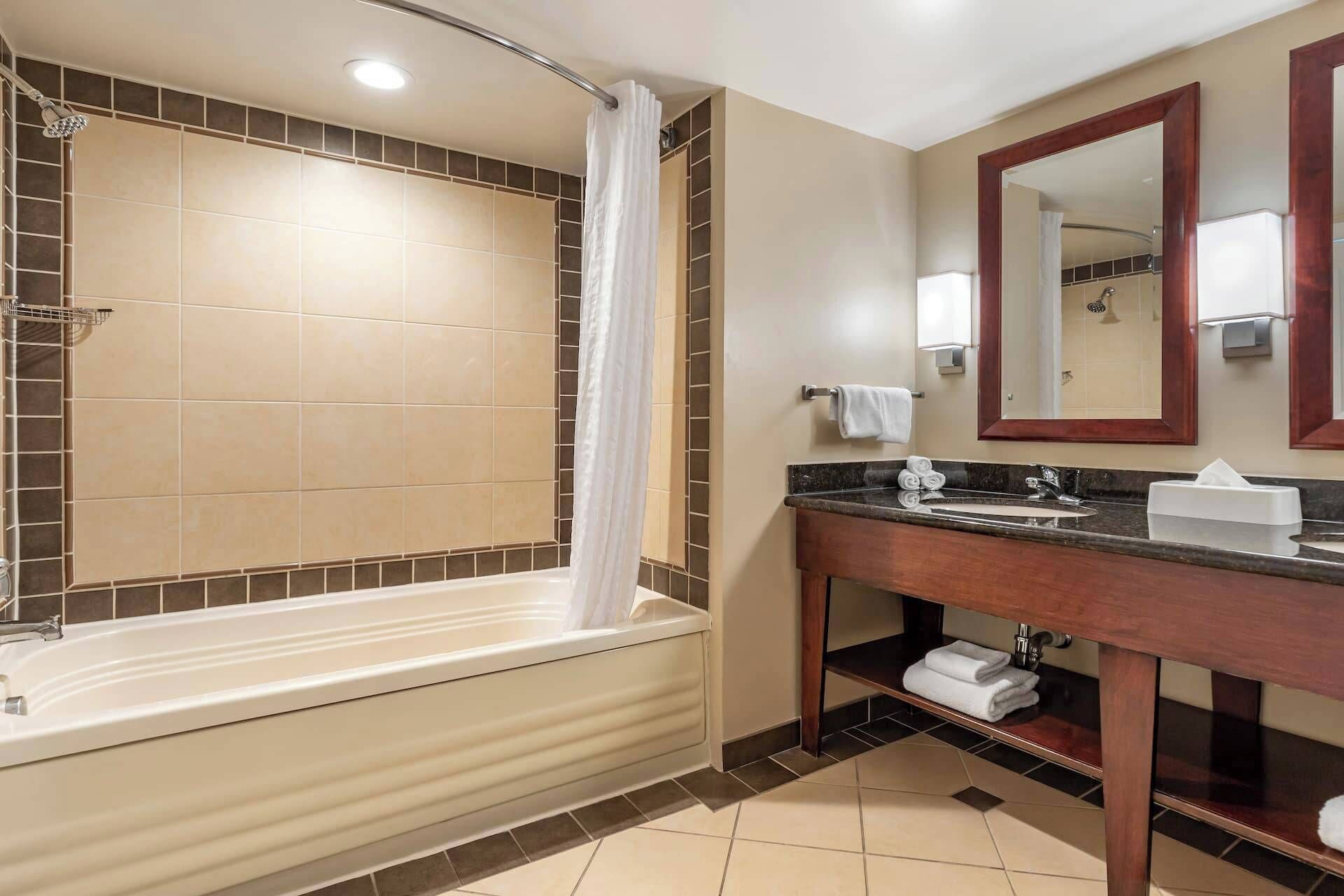 A modern bathroom with a bathtub, a vanity with a mirror, and a shower area.