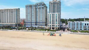 Ein Hotel direkt am Strand mit mehreren Hochhäusern, einem Sandstrand und einem Spielbereich.