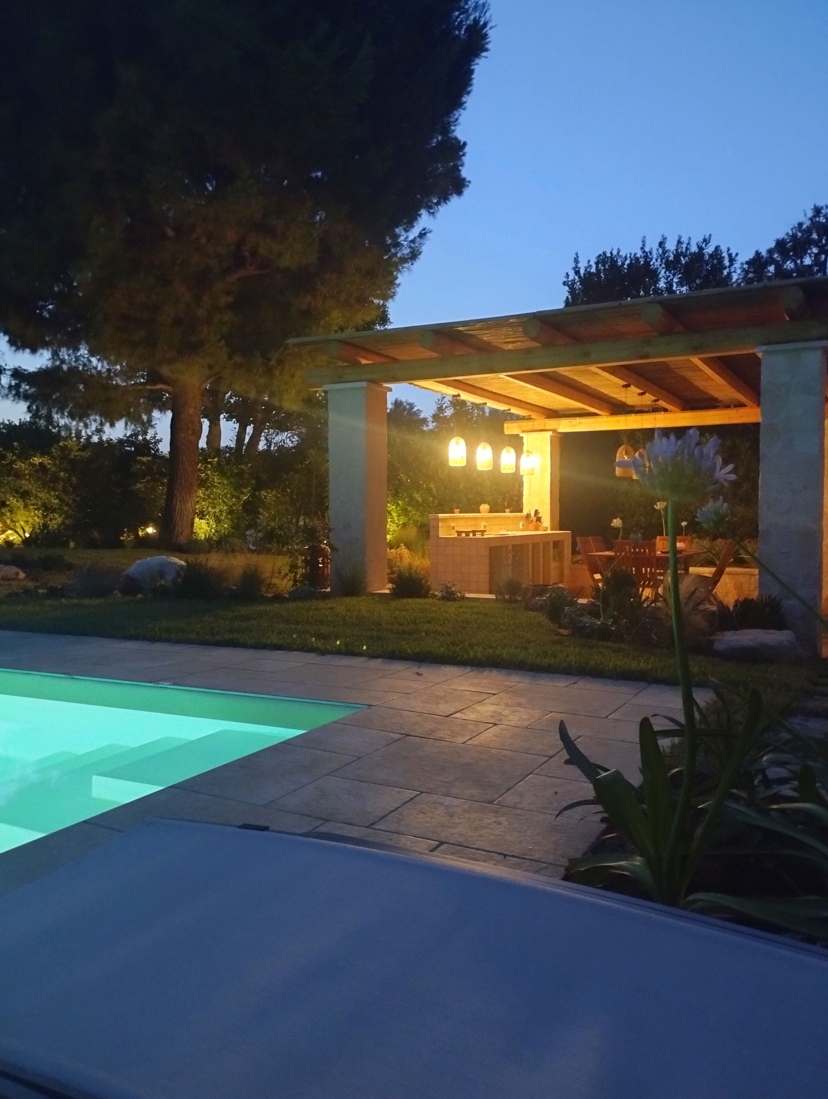 A poolside area with a pergola, outdoor seating, and a well-maintained garden.