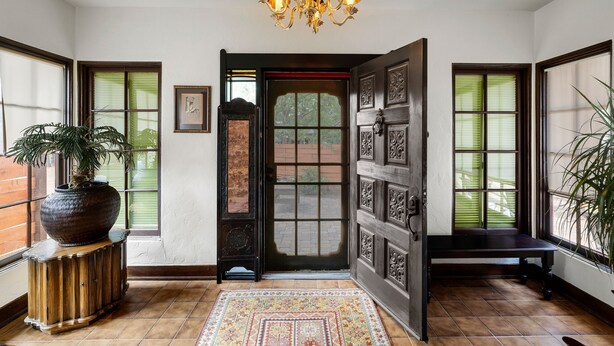 Un hall d’entrée spacieux, agrémenté d’un grand banc en bois, d’une plante en pot et d’un tapis à motifs.
