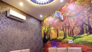 Un área de estar moderna con un sofá modular, una mesa de centro y un mural con una escena de bosque.