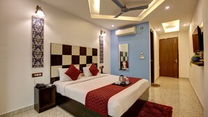 Una habitación de hotel moderna con una cama grande, un ventilador de techo, un equipo de aire acondicionado y una puerta de madera.