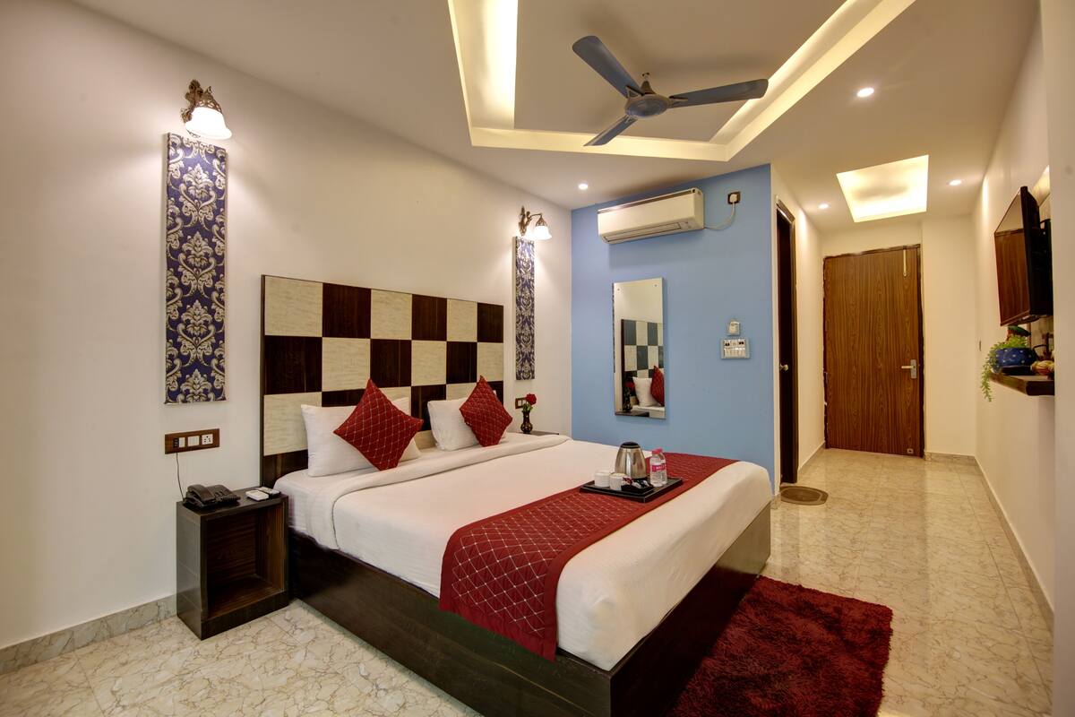 Una habitación de hotel moderna con una cama grande, un ventilador de techo, un equipo de aire acondicionado y una puerta de madera.
