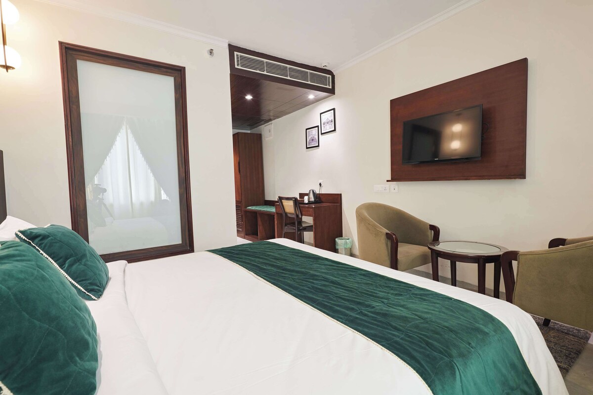 Une chambre d’hôtel équipée d’un lit, d’un bureau, d’une chaise, d’une télévision et d’une porte coulissante.