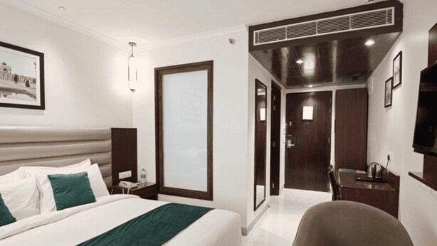 Une chambre d’hôtel équipée d’un lit, d’une chaise, d’un bureau, d’une télévision et d’une porte donnant accès à une salle de bain.