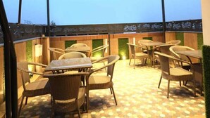 An outdoor patio with hexagonal patterned flooring, wicker furniture, and a pergola with lights. - Tango Traxx (Amritsar)