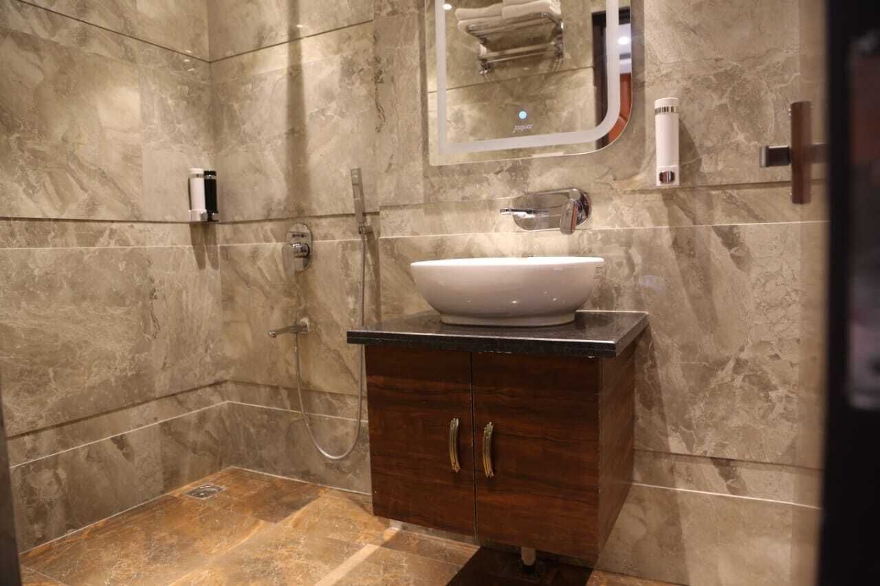 Ein Badezimmer mit Marmorwand, Waschbecken in Weiß, Holzschrank und Spiegel.
