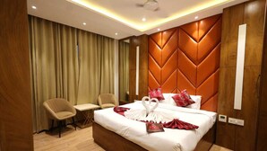 A hotel room with a large bed, two chairs, a desk, and a wooden headboard. - Tango Traxx (Amritsar)