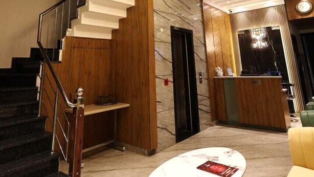 A modern hotel lobby with a marble staircase, a reception desk, and a round coffee table. - Tango Traxx (Amritsar)
